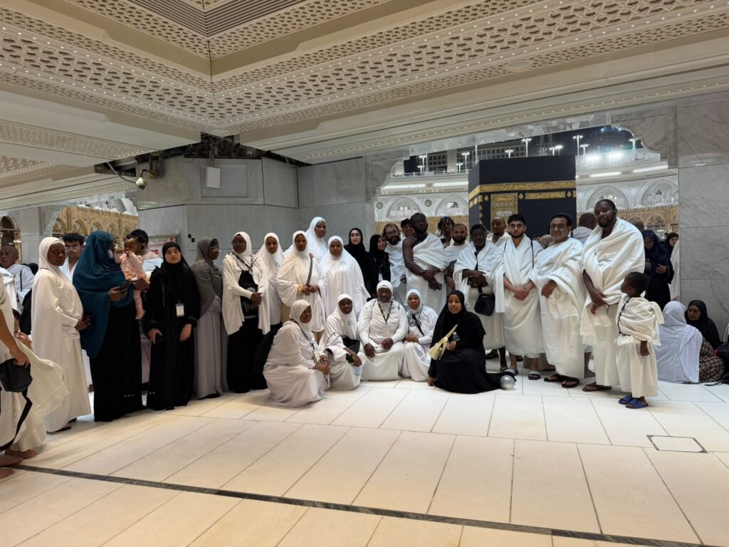 A group of Kasfah Hajj pilgrims posing together with the Kaaba in the background