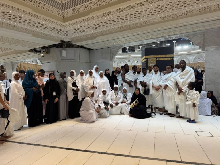 A group of Kasfah Hajj pilgrims posing together with the Kaaba in the background